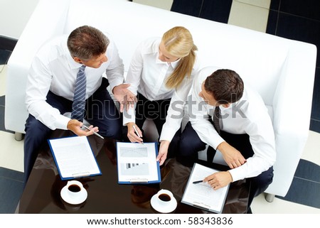 Image of company of successful partners discussing business plan at meeting