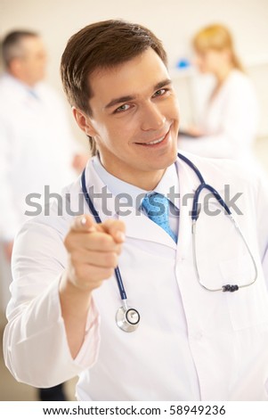 Portrait of friendly therapist pointing at you and looking at camera with smile