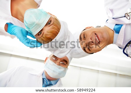 Below view of happy doctors and nurse in mask looking at camera