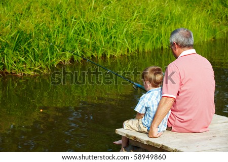Photo of grandfather and grandson sitting on pontoon and fishing on weekend
