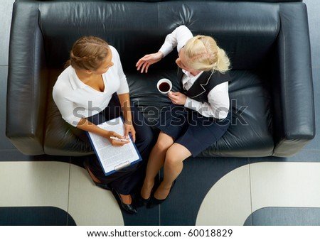 Above angle of two friendly employees sitting on sofa and planning work