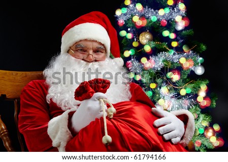 Santa sitting with a sack at the Christmas tree