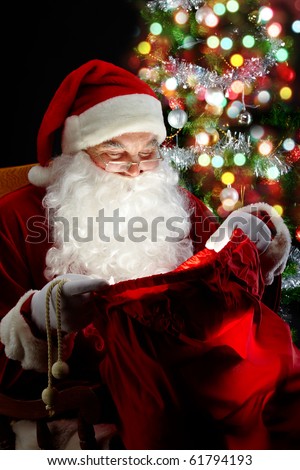 Santa sitting at the Christmas tree and looking into the sack