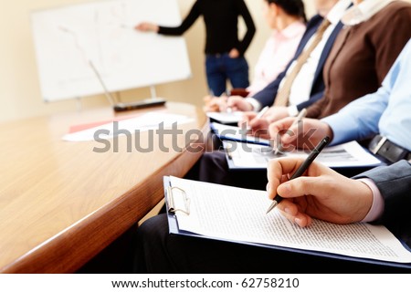 Close-up of businesspeople hands holding pens and papers near table at business seminar
