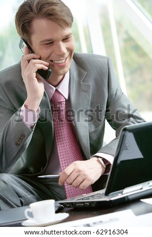 Portrait of a businessman sitting at computer and speaking on the telephone
