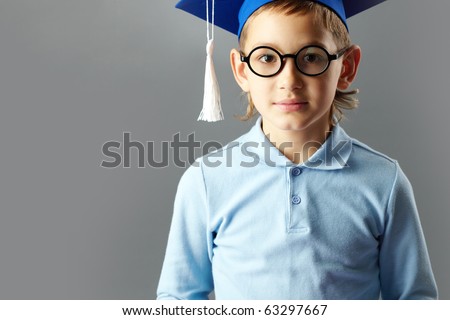 Portrait of cute guy in eyeglasses and bachelor hat looking at camera