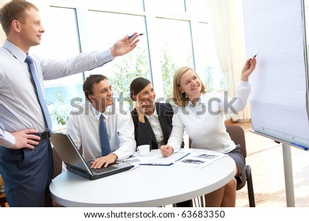 Image of business partners pointing at board during presentation in office