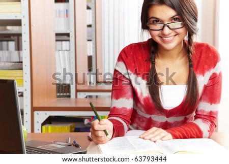 Portrait of clever student preparing lessons in college library