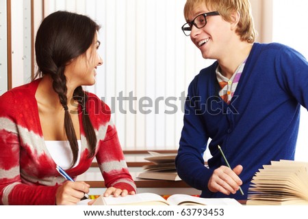 Portrait of clever students chatting while preparing lessons in college library
