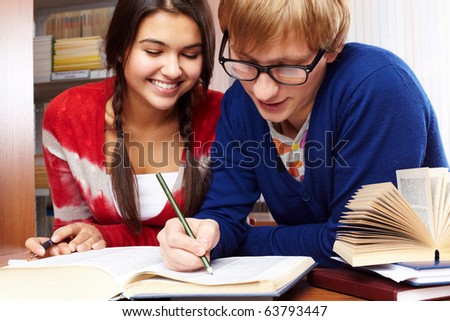 Portrait of clever students preparing lessons together in college library