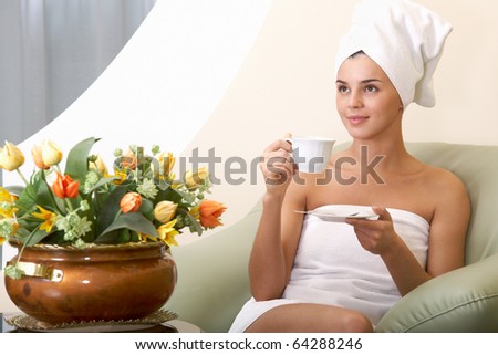Portrait of clean girl with towel on head drinking tea in beauty salon