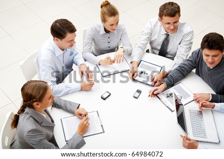 Image of company of successful partners looking at their colleague at meeting