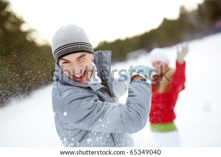 Image of attractive young man laughing during snowball play