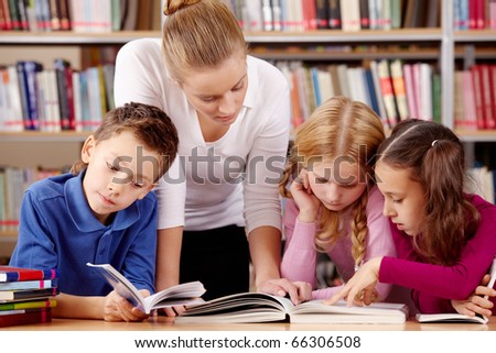 Portrait of pupils and teacher reading interesting book in library