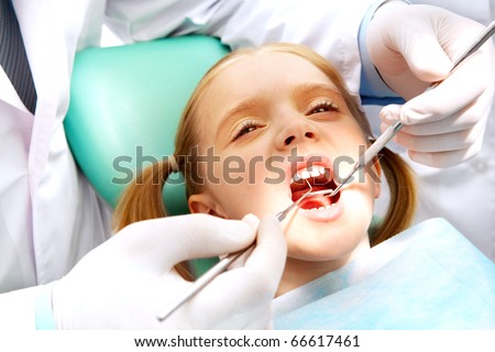 Photo of small girl with open mouth while it being examined by dentist