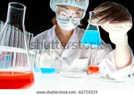 Laboratory worker looking at bottle with liquid during scientific experiment in laboratory