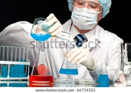 Serious clinician pouring blue liquid into glass tube in laboratory