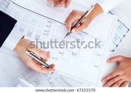 Close-up of engineers hands with pens over blueprints with sketches of projects