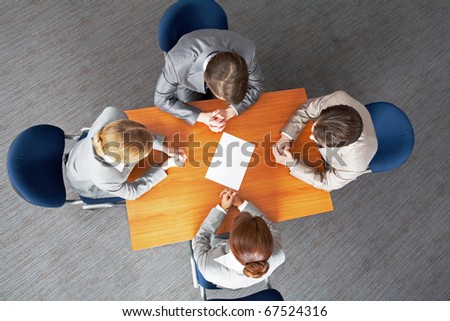 Above view of business people around table with blank paper in center