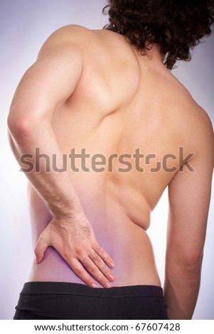 Back view of young man touching aching back