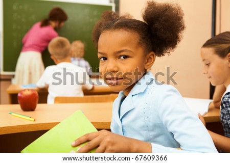 Portrait of cute girl looking at camera at workplace during lesson