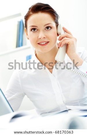 Portrait of pretty businesswoman calling in office
