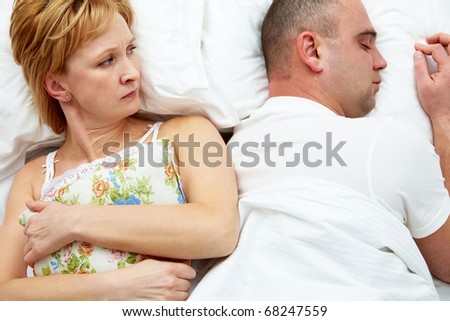 Photo of displeased wife holding pillow looking her husband
