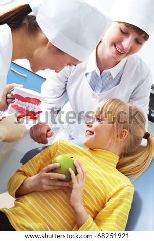 Photo of dentist teaching care dental hygiene little girl with assistant near by