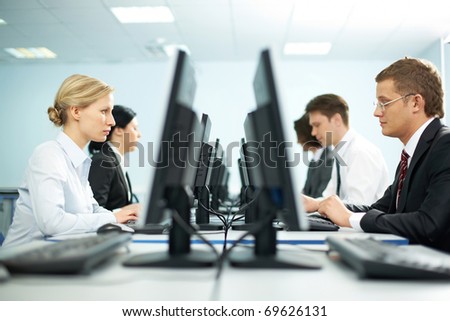 Two rows of businesspeople working on computers