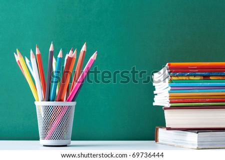 Image of crayons and exercise books against blackboard
