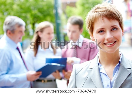 Portrait of pretty employee smiling at camera in a natural environment