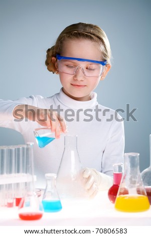 A little girl pouring liquid into a flask