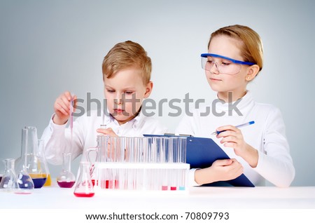 A little boy mixing chemical liquids and his assistant making notes