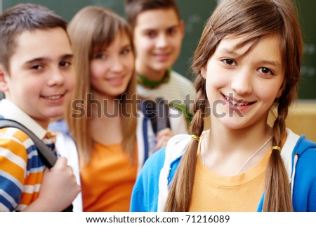 Confident student looking at camera with her friends behind