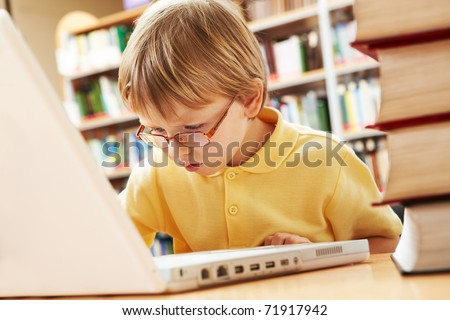 Portrait of serious schoolkid working with laptop in the library