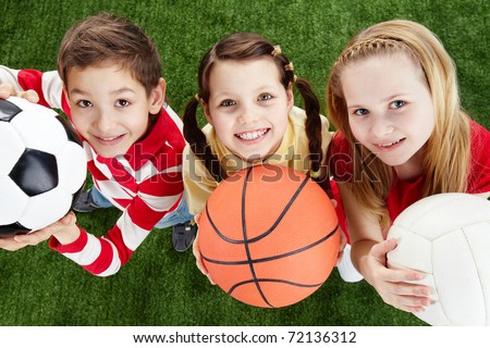 Image of happy friends on the grass with balls looking at camera Image of happy friends on the grass with balls looking at camera