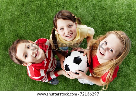 Image of happy friends on the grass with ball looking at camera