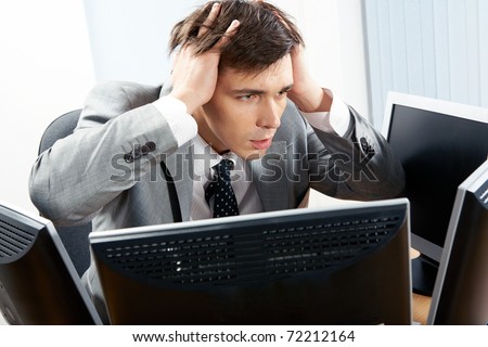 Portrait of frustrated employer sitting in front of computer with his hands on head