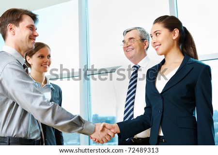 Photo of successful partners handshaking after signing agreement at meeting