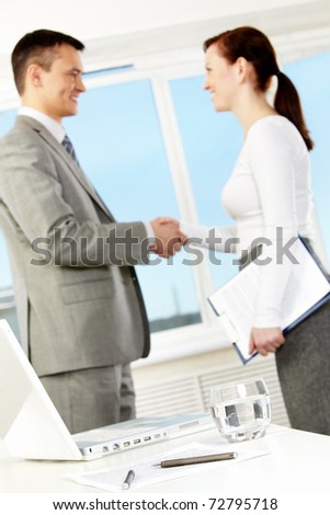 Photo of business objects at workplace with business partners handshaking after making agreement