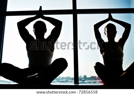 Photo of meditating people sitting with their arms raised and kept in touch