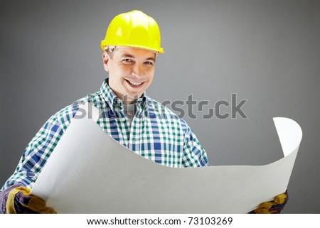 Portrait of a smiling worker in helmet holding a plan