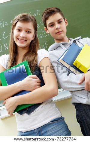 Portrait of happy guy and girl with books looking at camera