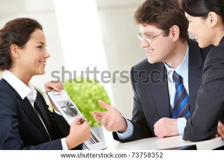 Photo of smart woman holding paper in hand with her two colleagues looking at her with smiles