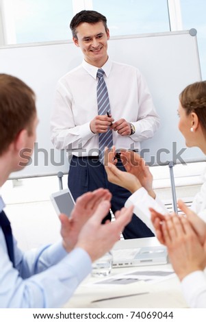 Photo of successful businessman standing by whiteboard while his partners applauding