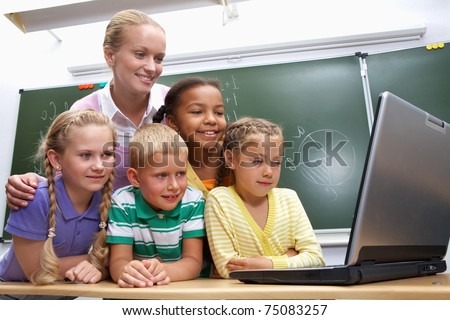 Portrait of pupils looking at the laptop with teacher near by