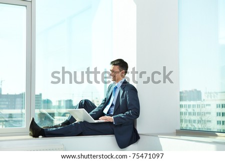 Portrait of confident man sitting with laptop in office