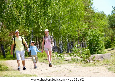Portrait of three family members walking down road at summer