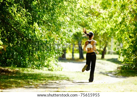 A young girl jogging in the park along trees A young girl jogging in the park along trees