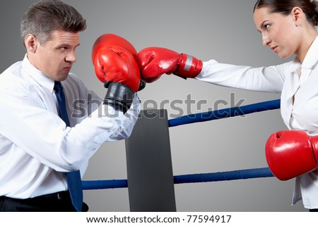 Portrait of aggressive businessman in boxing gloves fighting with serious female opposite him